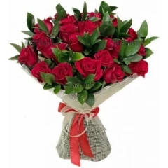 Classic bouquet of red roses and fresh greeenry, wrapping gift paper, tied with a ribbon.