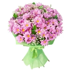 Tender, caressing bouquet of pink chrysanthemums, a lot of gypsophila and greenery, wrapped in gift paper.