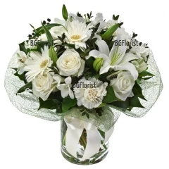 Bouquet of white flowers - lilies, roses, gerberas and carnations, wrapped in fresh greenery.