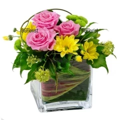 Sunny and beautiful arrangement with delicate pink roses, sunny yellow chrysanthemums and greenery in glass cube.