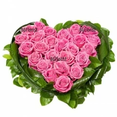 Аранжировка във формата на сърце - нежни розови рози, обгърнати със свежа зеленина.
