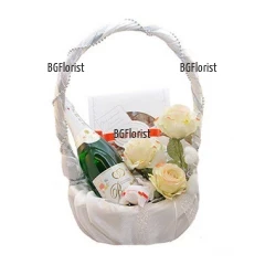 Тази прекрасна кошница с цветя и подаръци, обвита в сатен е много подходящ подарък за сватбения ден на младата двойка.